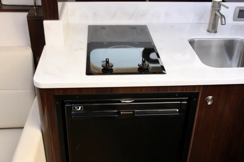 Slide: The Image of 2017 Sea Ray Sundancer 350 Coupe kitchen with stove, sink, and compact refrigerator. - 31