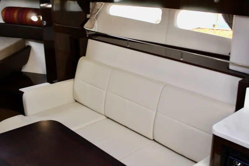 Slide: The Image of Interior of 2017 Sea Ray Sundancer 350 Coupe with white leather seating and dark wood accents. - 32