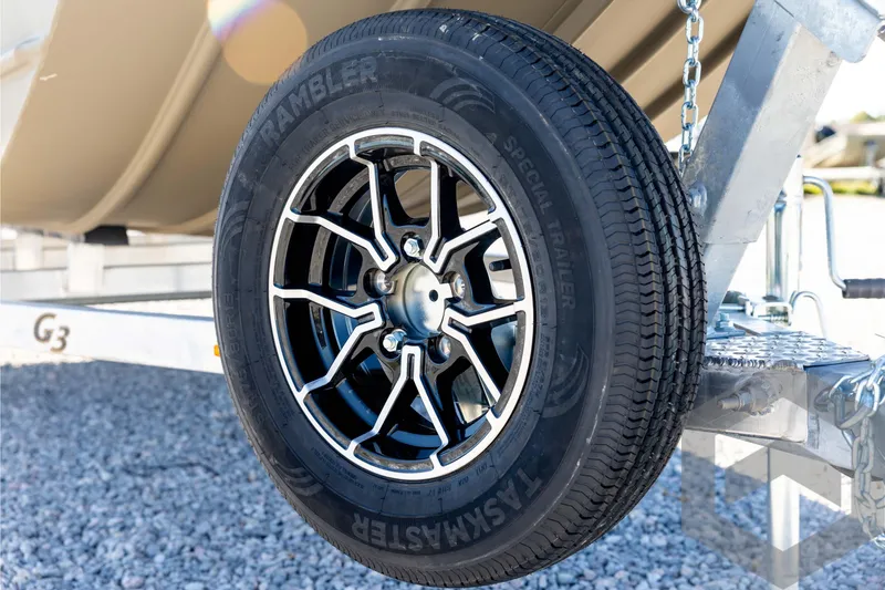 Slide: The Image of Trailer wheel on a 2026 G3 1652 VBW boat trailer, parked on gravel. - 10