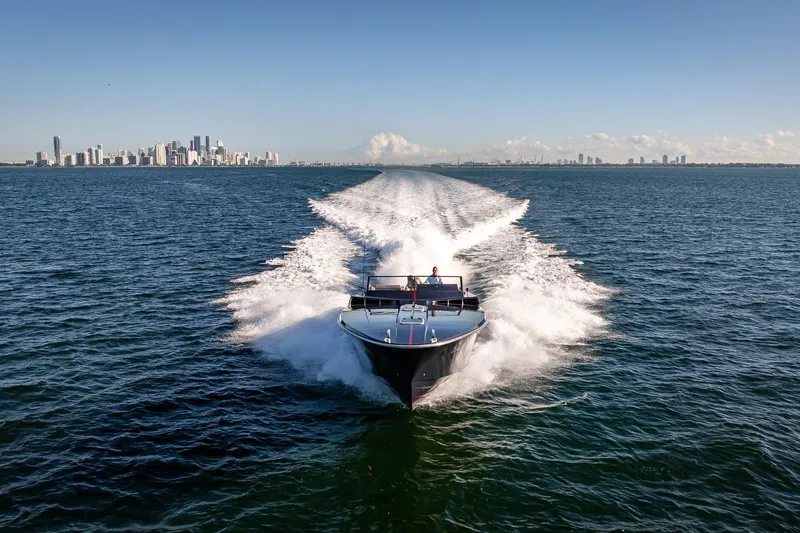 Slide: The Image of Speeding Magnum 50 Bestia yacht on open water, city skyline in background, clear blue sky. - 19