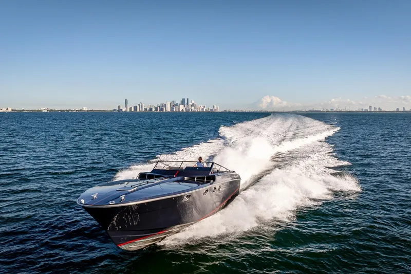 Slide: The Image of Sleek Magnum 50 Bestia yacht cruising on open water, city skyline in background. - 20