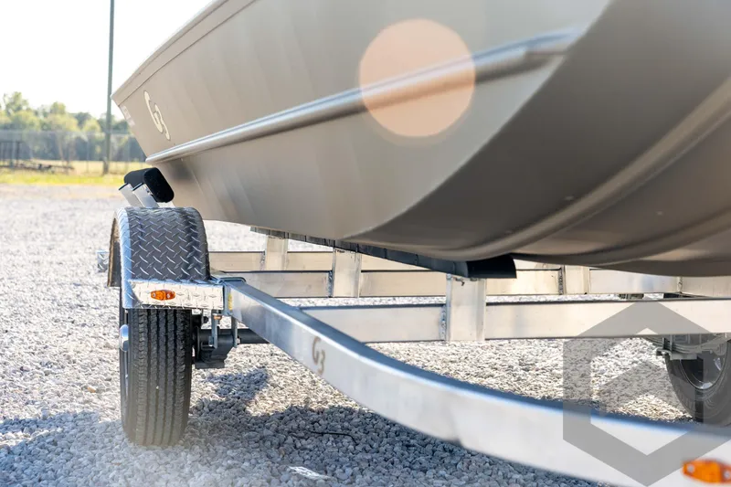 Slide: The Image of 2026 G3 1652 VBW boat on trailer, parked on gravel, sunlight reflecting. - 13