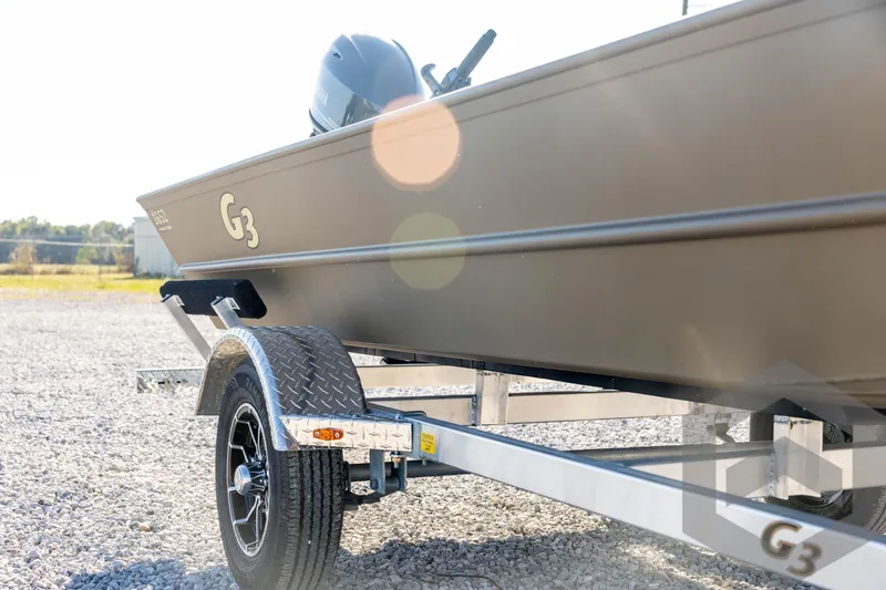 Slide: The Image of 2026 G3 1652 VBW boat on trailer, parked on gravel, with sunlight reflections. - 14