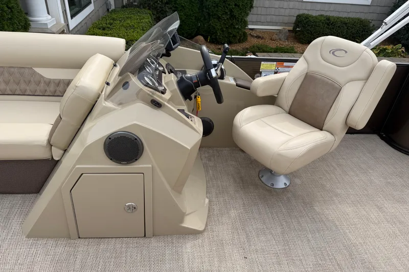 Slide: The Image of 2019 Crest II 240 SLS pontoon boat with beige seating and helm, parked outdoors. - 6