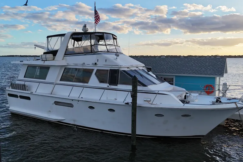 The Image of 1987 Viking Gulfstar yacht docked by a blue houseboat at sunset. - 3