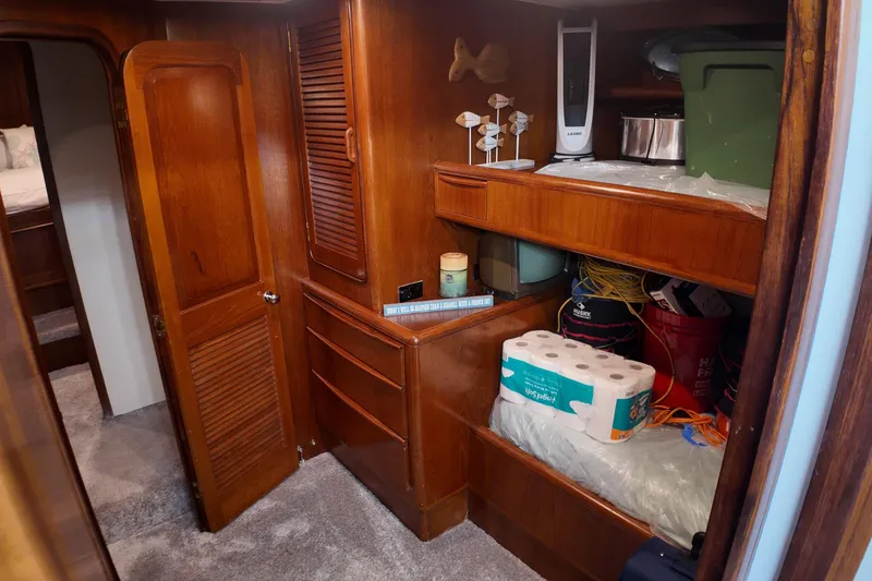 Slide: The Image of 1987 Viking Gulfstar interior with wooden cabinets, storage shelves, and various household items. - 46