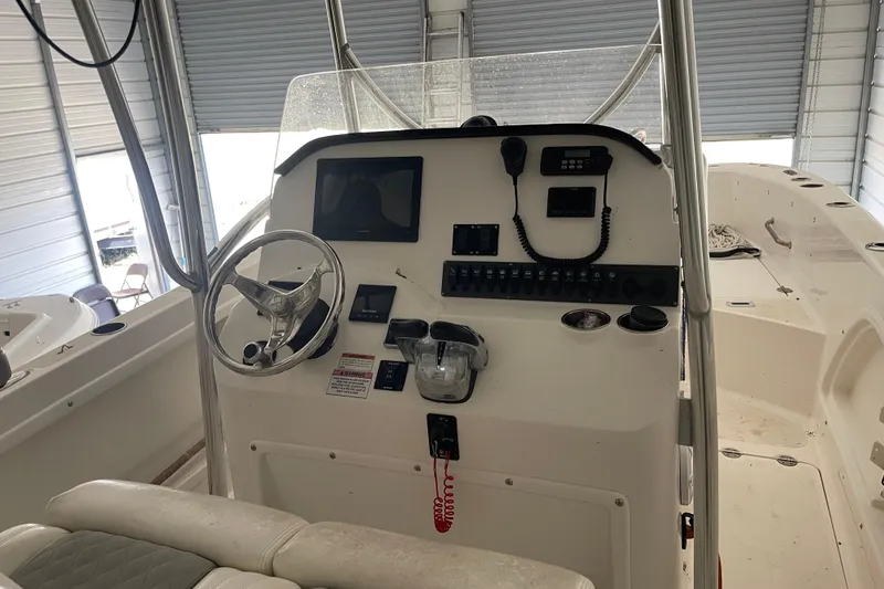 The Image of 2020 Twin Vee 230 JP CC boat console with steering wheel and controls in a garage. - 1