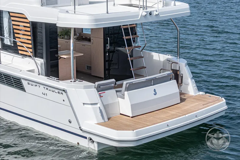 Slide: The Image of 2026 Beneteau Swift Trawler 41 Fly, rear view on water, showcasing deck and ladder. - 3