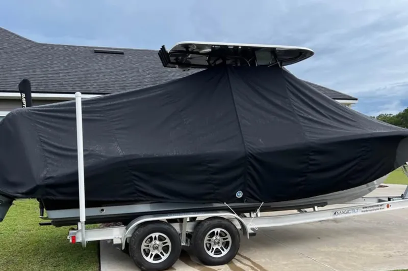 Slide: The Image of 2022 NauticStar 2302 Legacy boat covered on trailer, parked in driveway. - 7