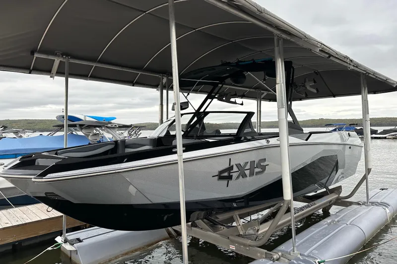 The Image of 2025 Axis A245 boat docked under a canopy on a lake. - 0