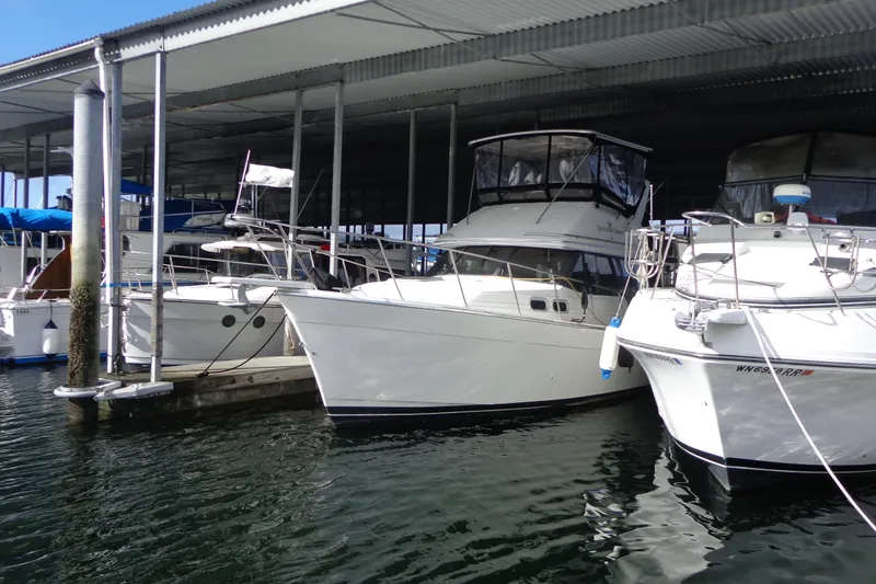 Slide: The Image of 1992 Bayliner 3288 Motoryacht docked in a marina, partially covered, side view. - 2
