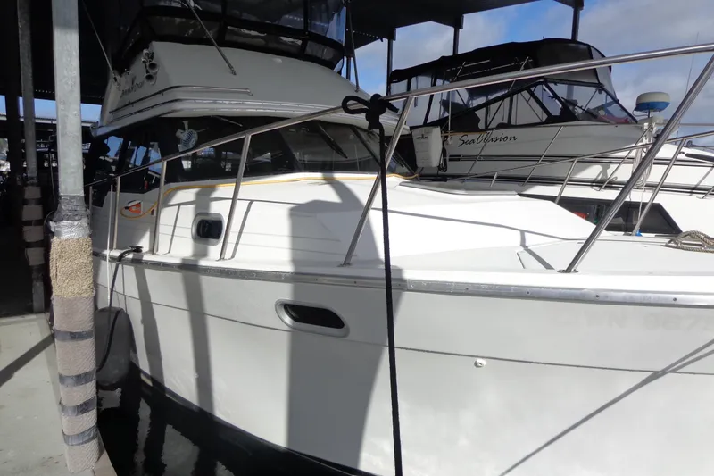 Slide: The Image of 1992 Bayliner 3288 Motoryacht docked in a marina, partially shaded. - 9