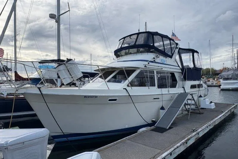 Slide: The Image of 1987 Tollycraft 34 Sundeck Motor Yacht docked at marina under cloudy sky. - 0
