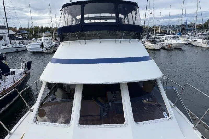 Slide: The Image of 1987 Tollycraft 34 Sundeck Motor Yacht docked in a marina, surrounded by boats. - 10