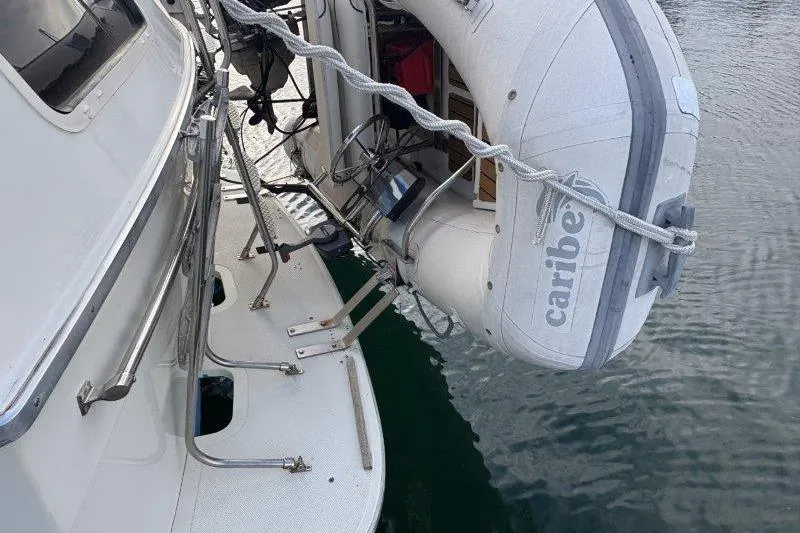 Slide: The Image of 1987 Tollycraft 34 Sundeck Motor Yacht with attached inflatable dinghy on water. - 12