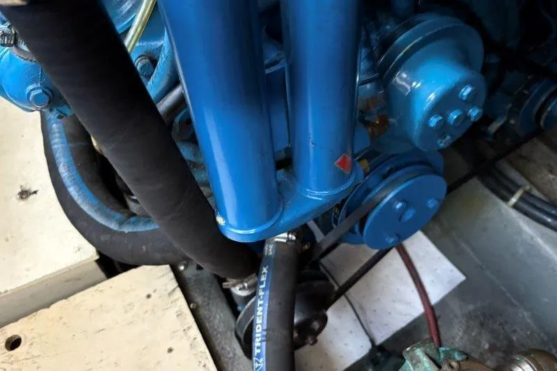 Slide: The Image of Engine components of a 1987 Tollycraft 34 Sundeck Motor Yacht, featuring blue hoses and parts. - 57