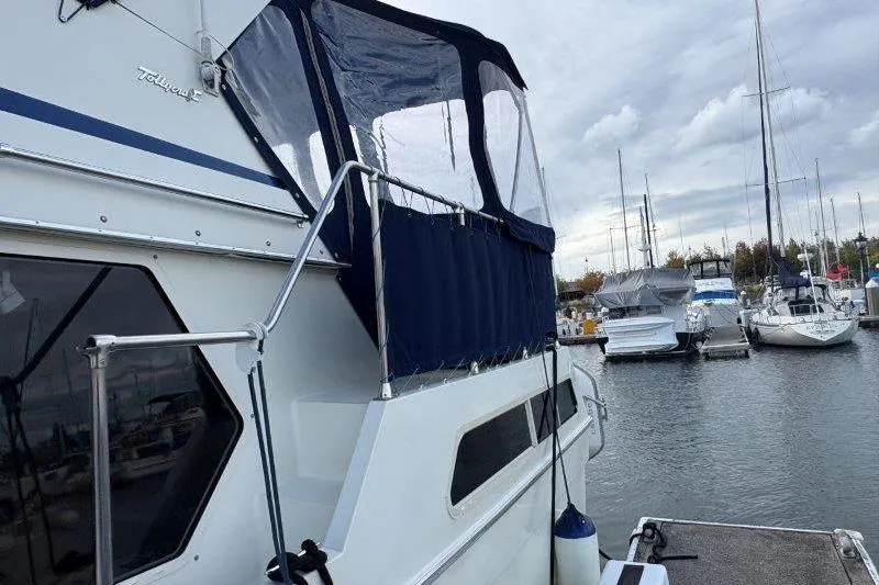 Slide: The Image of 1987 Tollycraft 34 Sundeck Motor Yacht docked at marina, featuring blue canopy. - 7