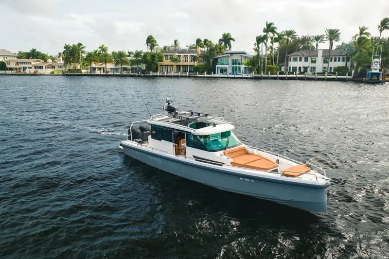 Slide: The Image of 2018 Axopar 37 Sport Cabin cruising on a scenic waterfront with luxury homes. - 0