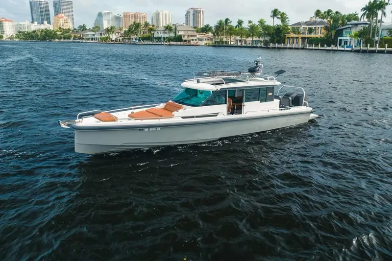 Slide: The Image of 2018 Axopar 37 Sport Cabin cruising on a scenic waterfront with city skyline. - 2