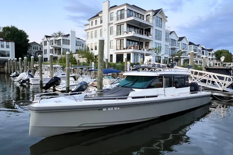 Slide: The Image of 2018 Axopar 37 Sport Cabin docked near modern waterfront buildings. - 9