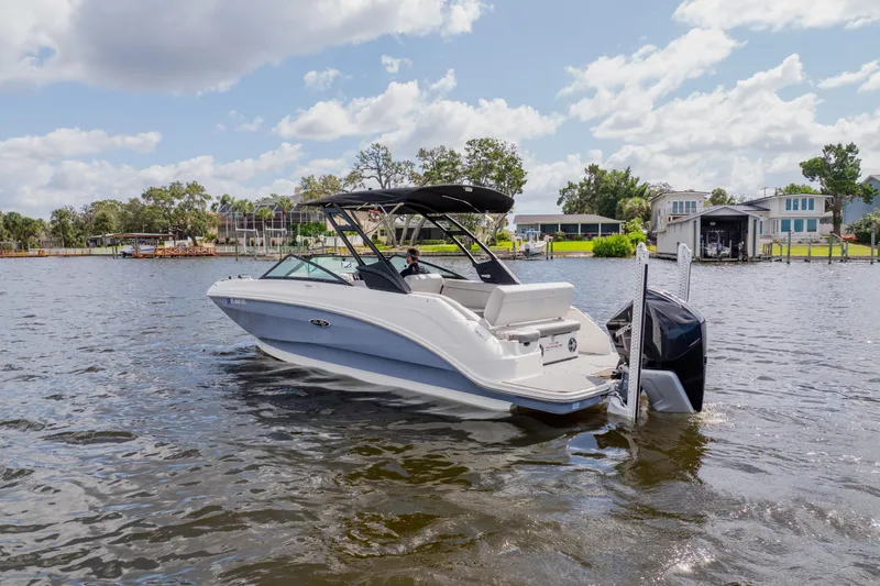 Slide: The Image of 2021 Sea Ray SDX 250 Outboard boat on a sunny lake with houses in the background. - 2