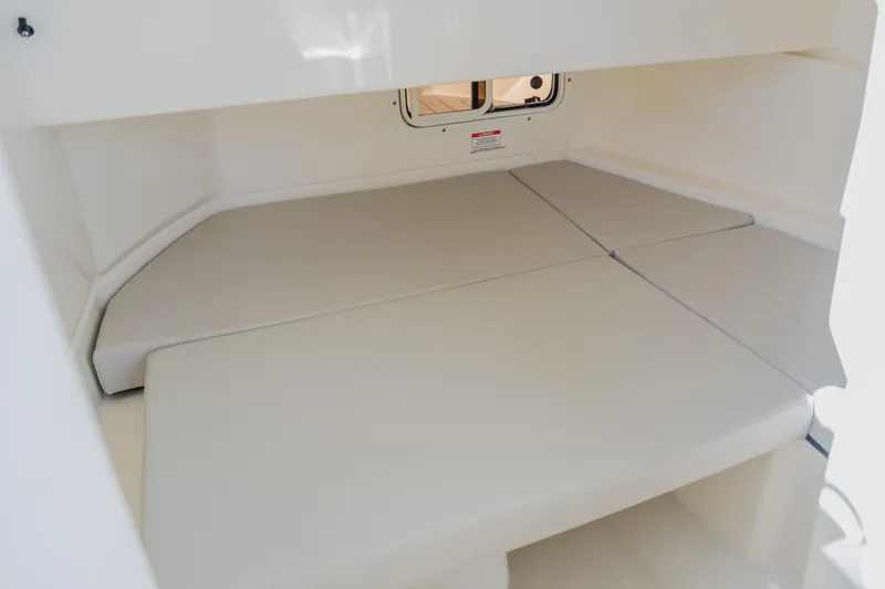 Slide: The Image of 2021 Sea Ray SDX 250 Outboard cabin interior with cushioned seating and small window. - 48