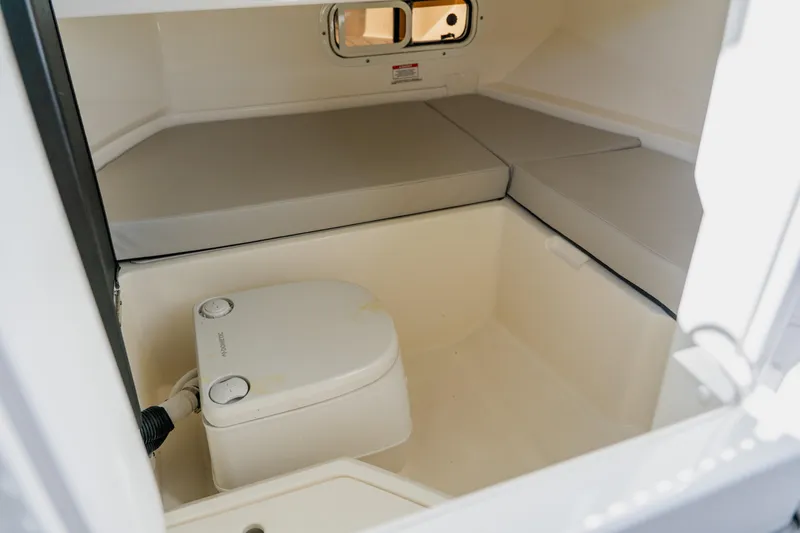 Slide: The Image of 2021 Sea Ray SDX 250 Outboard cabin interior with compact toilet and cushioned seating. - 50