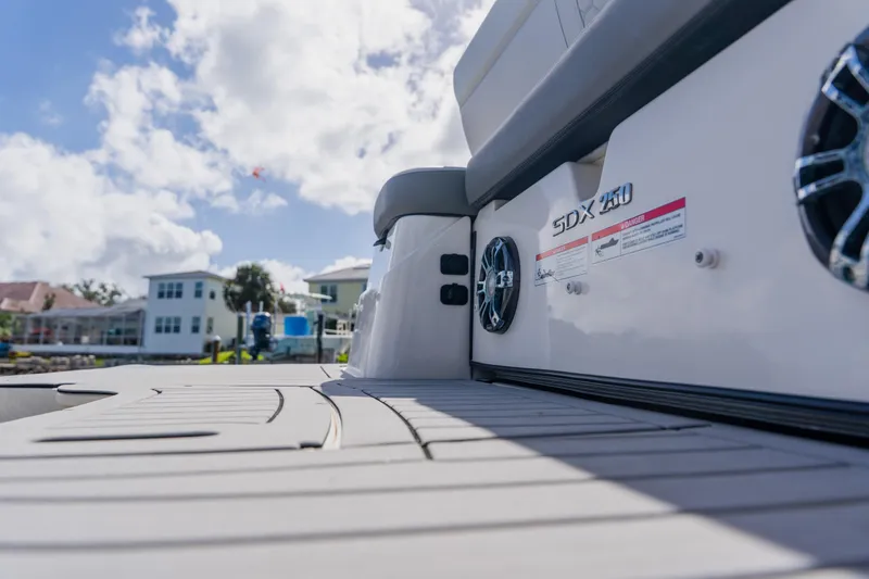 Slide: The Image of 2021 Sea Ray SDX 250 Outboard boat deck with speakers, under a bright blue sky. - 77