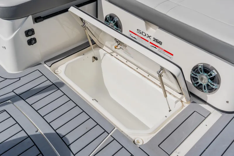 Slide: The Image of 2021 Sea Ray SDX 250 Outboard boat storage compartment with open hatch and speakers. - 78