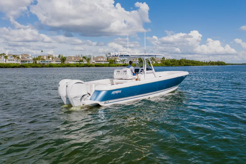Slide: The Image of 2018 Intrepid 327 Center Console boat cruising on a sunny day, with scenic waterfront homes. - 2