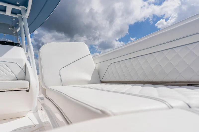 Slide: The Image of 2018 Intrepid 327 Center Console with white quilted seating under a cloudy sky. - 40