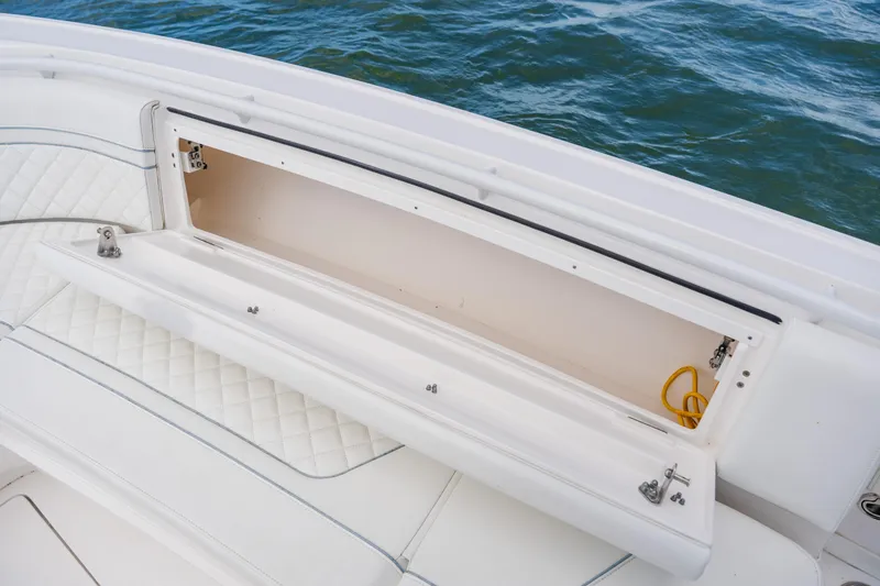 Slide: The Image of 2018 Intrepid 327 Center Console storage compartment with quilted seating, open on calm water. - 48