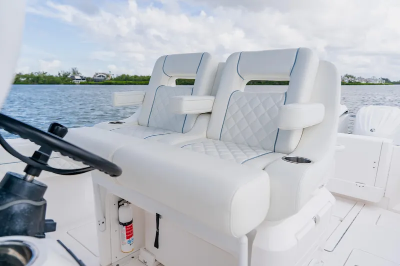 Slide: The Image of 2018 Intrepid 327 Center Console boat with luxurious white seating on a calm water backdrop. - 73