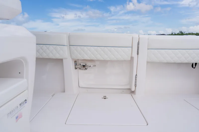 Slide: The Image of 2018 Intrepid 327 Center Console boat interior with white cushioned seating and storage hatch. - 83