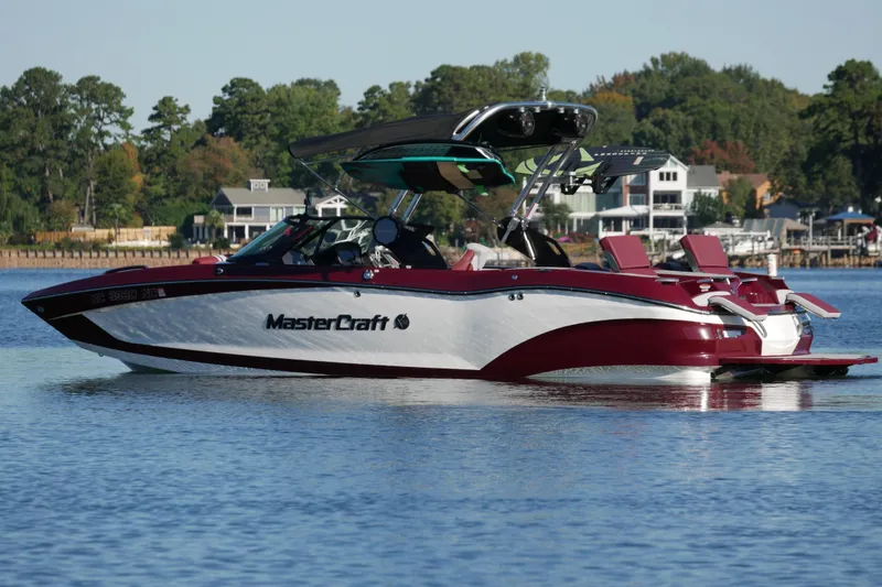 The Image of 2022 MasterCraft X22 boat on a calm lake with scenic background. - 1