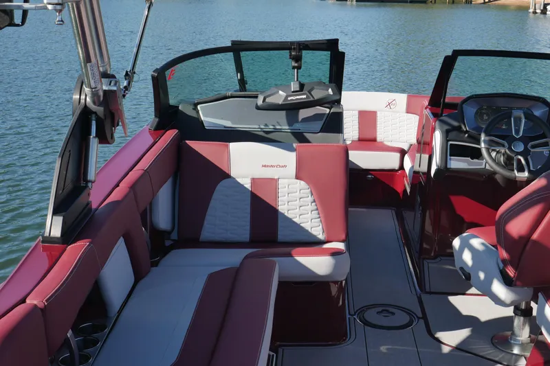 Slide: The Image of 2022 MasterCraft X22 boat interior with red and white seating, steering wheel, and lake view. - 12