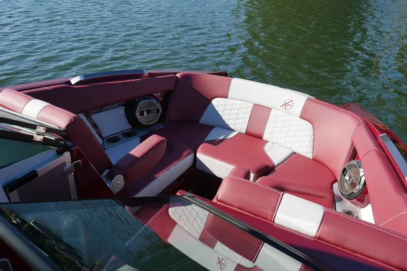 Slide: The Image of 2022 MasterCraft X22 boat interior with red and white seating on water. - 14