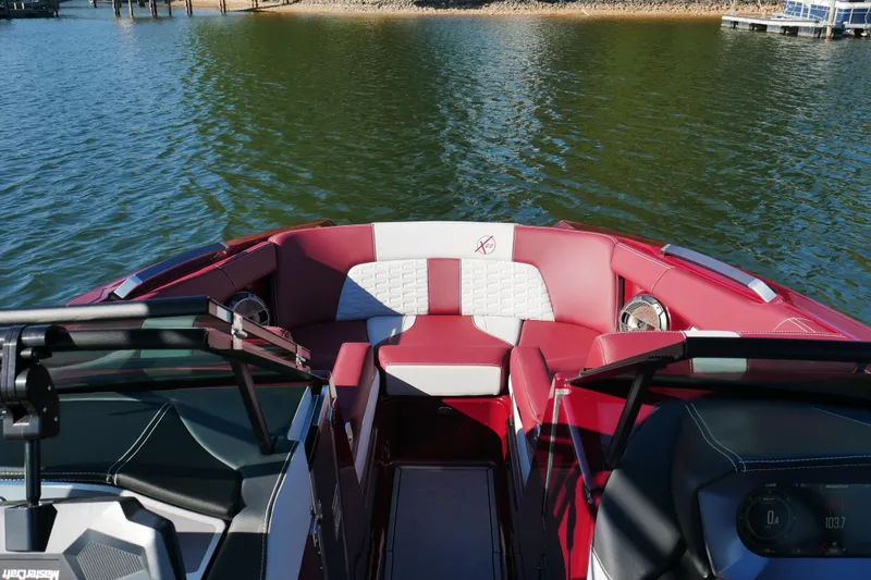 Slide: The Image of 2022 MasterCraft X22 boat interior with red and white seating on a lake. - 15
