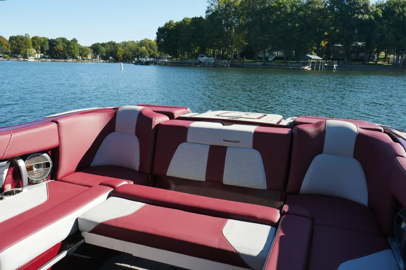 Slide: The Image of 2022 MasterCraft X22 boat interior with red and white seating on a lake. - 18