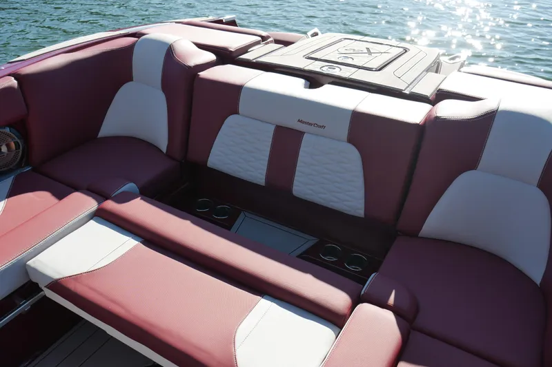 Slide: The Image of 2022 MasterCraft X22 boat interior with maroon and white seating on water. - 19