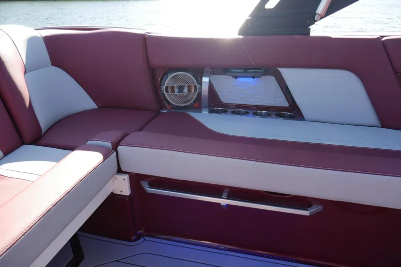 Slide: The Image of 2022 MasterCraft X22 boat interior with maroon and white seating, cup holders, and speaker. - 20