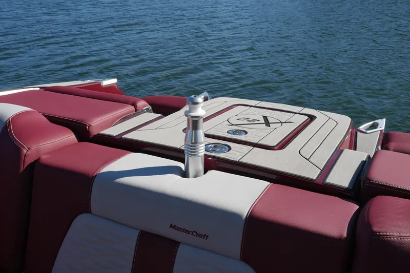 Slide: The Image of 2022 MasterCraft X22 boat with maroon and white seating on a calm lake. - 22