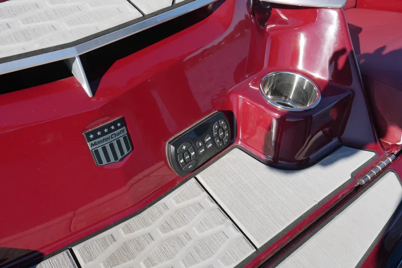 Slide: The Image of 2022 MasterCraft X22 boat interior with red finish, control panel, and cup holder. - 24