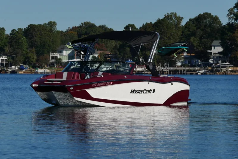 Slide: The Image of 2022 MasterCraft X22 boat on a lake, surrounded by trees and houses. - 5