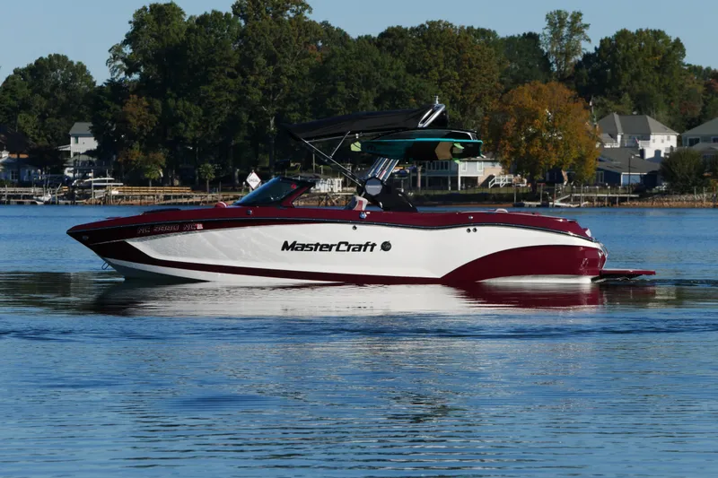 Slide: The Image of 2022 MasterCraft X22 boat on a calm lake with trees in the background. - 6