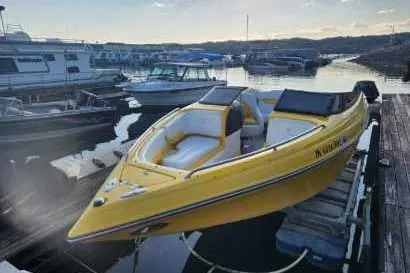 Slide: The Image of 2003 Crownline 225 LPX boat in marina, yellow exterior, docked with other vessels. - 1