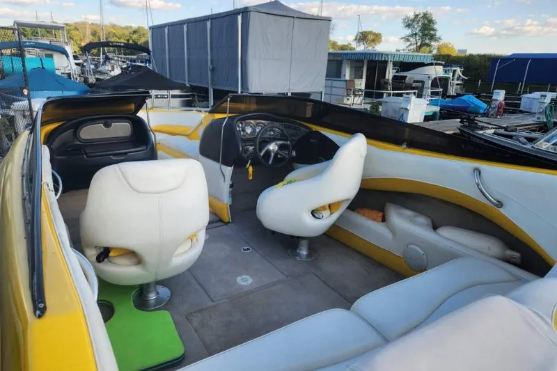Slide: The Image of 2003 Crownline 225 LPX boat interior with white and yellow seating, docked at a marina. - 2