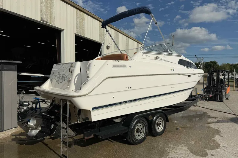 Slide: The Image of 1999 Bayliner 2655 Ciera boat on trailer outside a warehouse under a blue sky. - 9