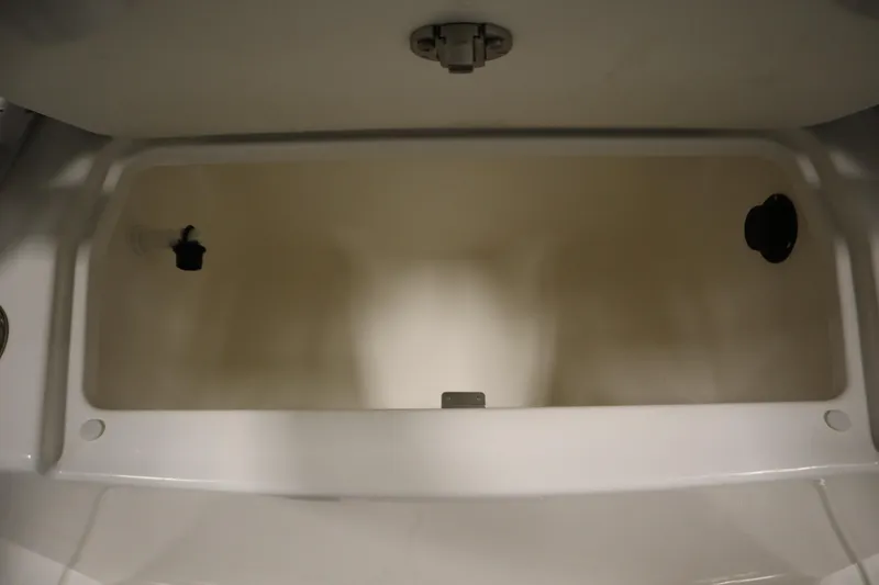 Slide: The Image of 2024 Bayliner Trophy T22CC storage compartment, open and empty, with latch and drainage features. - 33