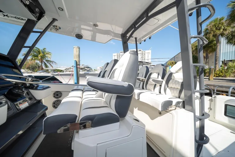 Slide: The Image of 2022 World Cat 400 CC-X boat interior with modern seating and helm, docked near palm trees. - 23